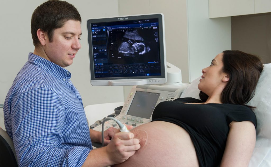Sonographer performing an obstetric ultrasound scan on a pregnant patient.