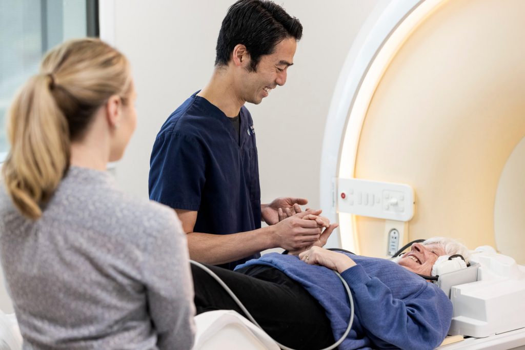 Radiographer caring for elderly patient having an MRI brain scan at Imaging Associates.